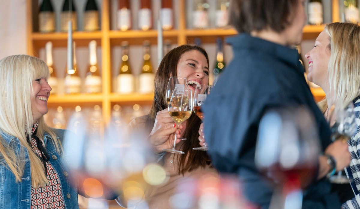 A group of people clink glasses of wine in a wine shop. Wine bottles can be seen on shelves in the background., © Stuttgart-Marketing GmbH, Thomas Niedermüller