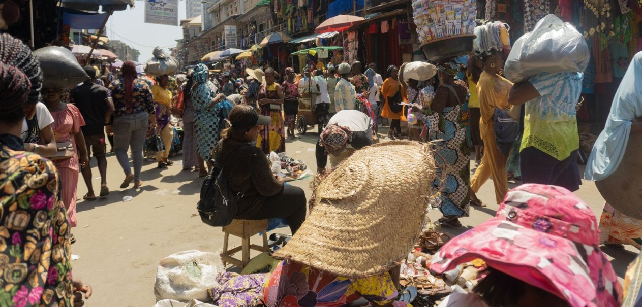 Belebter Markt in Lagos mit zahlreichen Menschen, die Waren kaufen und verkaufen. Farbenfrohe Kleidung und gesch&auml;ftiges Treiben pr&auml;gen das Bild., &copy; Dandara Maia