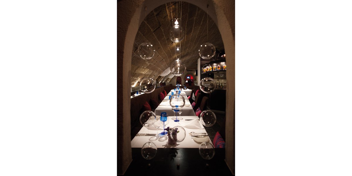 Elegantes Restaurant mit langer Tafel, dekoriert mit blauen Gläsern und schwebenden Glaskugeln., © Délice, Stuttgart Elegantes Restaurant mit langer Tafel, dekoriert mit blauen Gläsern und schwebenden Glaskugeln., © Délice, Stuttgart