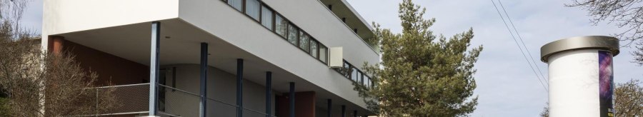 Modern building with a white façade and large windows, surrounded by trees and a billboard., © SMG Stuttgart Marketing GmbH - Sarah Schmid