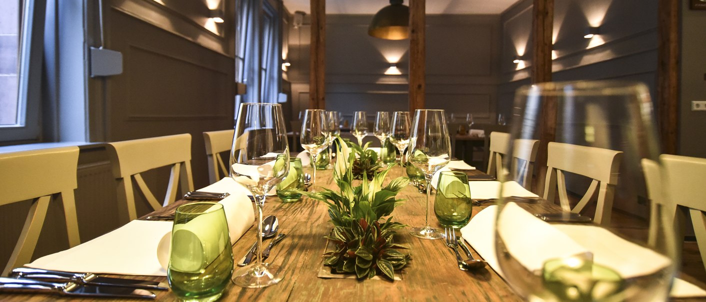 A stylishly laid dining table with wine glasses, green glasses and plants as decoration in an elegant room., © Classic Rock Café Gastronomie- Betriebs GmbH A stylishly laid dining table with wine glasses, green glasses and plants as decoration in an elegant room., © Classic Rock Café Gastronomie- Betriebs GmbH