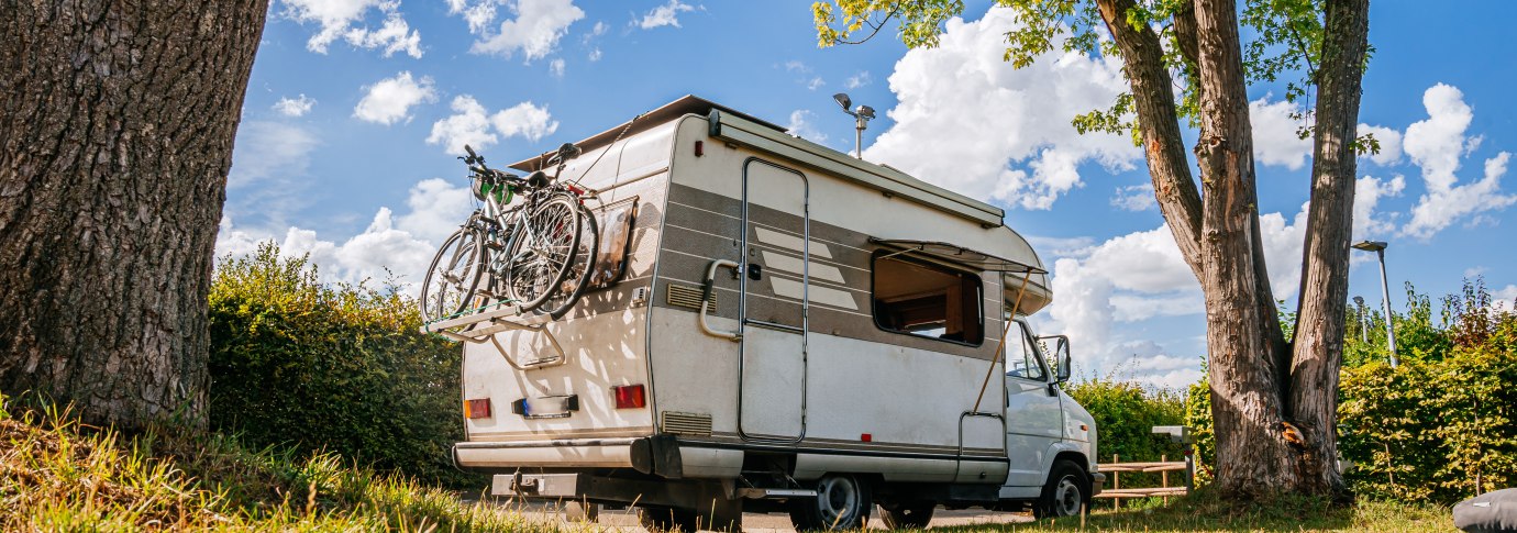 Ein Wohnmobil mit Fahrrädern am Heck steht auf einem grünen Stellplatz unter Bäumen. Der Himmel ist blau mit weißen Wolken., © Stuttgart-Marketing GmbH, Thomas Niedermüller