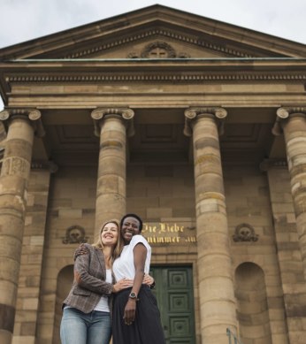 Two people embrace with a smile in front of the imposing façade of the Stuttgart burial chapel with its columns., © Stuttgart-Marketing GmbH, wpsteinheisser