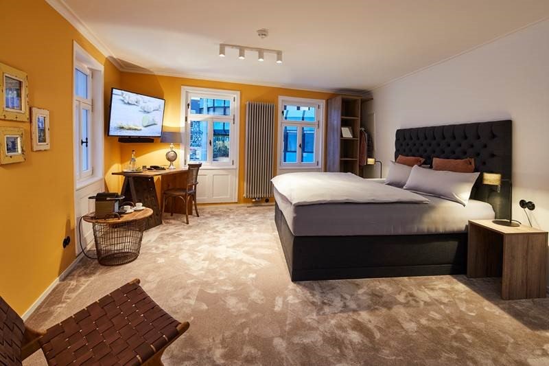Modernes Schlafzimmer mit Doppelbett, Schreibtisch, Fernseher und warmen Farben. Gro&szlig;e Fenster lassen viel Licht herein., &copy; Hotel Restaurant Bachofer