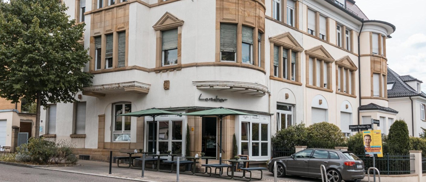 Ein Caf&eacute; namens Lamber an einer Stra&szlig;enecke mit Au&szlig;ensitzbereich und einem geparkten Auto davor., &copy; Stuttgart Marketing GmbH, Sarah Schmid