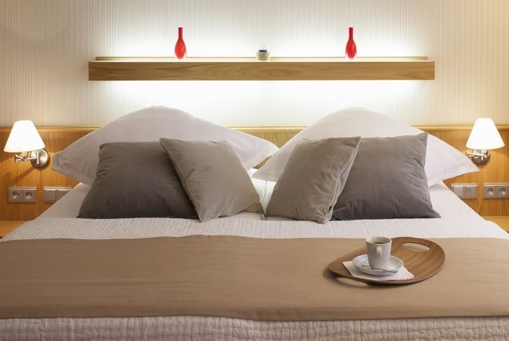 A modern bedroom with a double bed, decorated with pillows and a tray with a cup. Two red vases on a shelf in the background., © Hotel Drei Morgen A modern bedroom with a double bed, decorated with pillows and a tray with a cup. Two red vases on a shelf in the background., © Hotel Drei Morgen