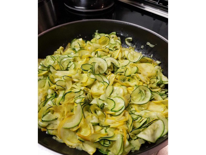 Yellow and green zucchini slices are cooked in a pan. They are thinly sliced and evenly distributed., &copy; Kultweine-Kochwelten-Kunst&uuml;cke - Kochschule Sonja Lenz