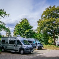 Wohnmobilstellplatz mit mehreren geparkten Wohnmobilen, umgeben von Bäumen und einem Haus im Hintergrund., © Stuttgart-Marketing GmbH, Thomas Niedermüller