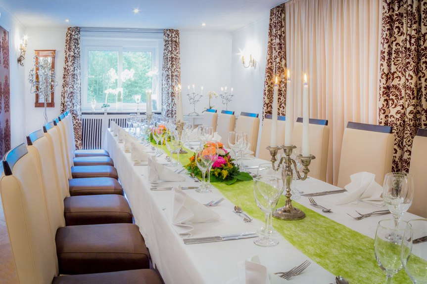 Eleganter Raum mit langem, gedecktem Tisch, Kerzenleuchtern und Blumendekoration. Große Fenster und verzierte Vorhänge schaffen eine festliche Atmosphäre., © Kulinarium an der Glems