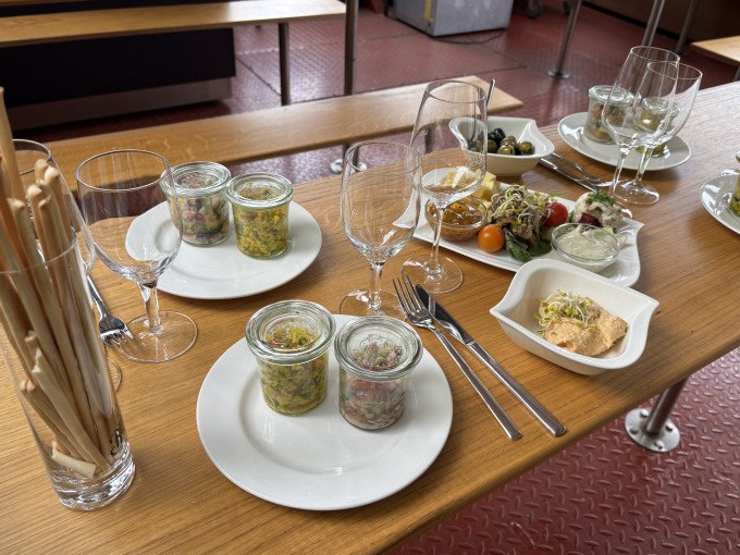 Ein Tisch mit Tapas in Gläsern, Weingläsern, Brotstangen und kleinen Tellern mit Oliven und Dips auf einem Holzbrett., © Cool-Tours StattReisen Ein Tisch mit Tapas in Gläsern, Weingläsern, Brotstangen und kleinen Tellern mit Oliven und Dips auf einem Holzbrett., © Cool-Tours StattReisen
