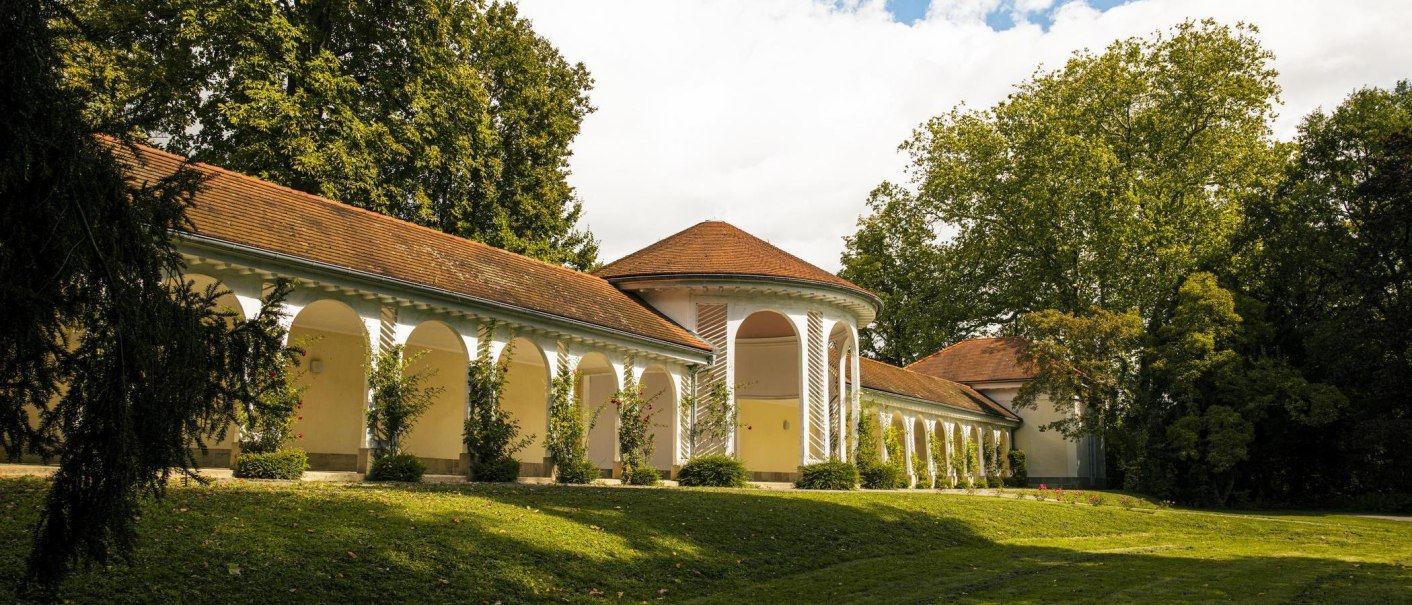 The lobby in Bad Boll features elegant arcades and a red-tiled roof, nestled in a green landscape with trees and lawns., © SMG Stuttgart Marketing GmbH - Sarah Schmid The lobby in Bad Boll features elegant arcades and a red-tiled roof, nestled in a green landscape with trees and lawns., © SMG Stuttgart Marketing GmbH - Sarah Schmid