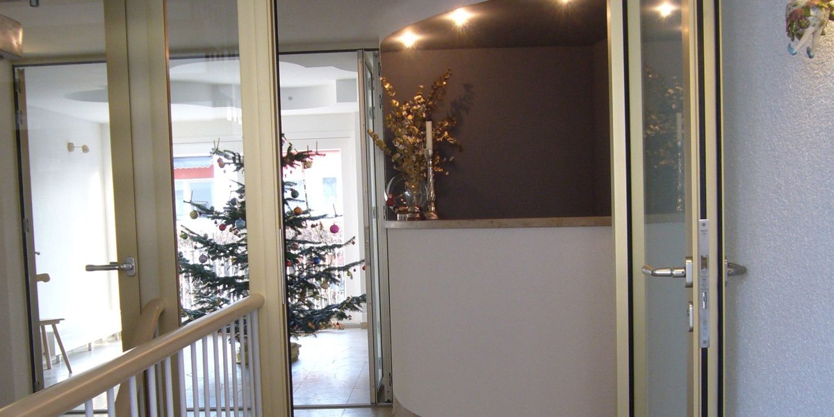 Eingangsbereich mit Glastüren, einem dekorierten Weihnachtsbaum und einer beleuchteten Ecke mit Kerzen und Pflanzen., © Hotelmärchen Eingangsbereich mit Glastüren, einem dekorierten Weihnachtsbaum und einer beleuchteten Ecke mit Kerzen und Pflanzen., © Hotelmärchen