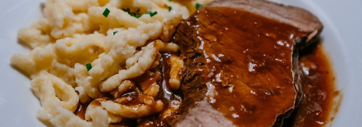 Ein Teller mit saftigem Braten in dunkler So&szlig;e, serviert mit Sp&auml;tzle, garniert mit Schnittlauch., &copy; SMG, Thomas Niederm&uuml;ller