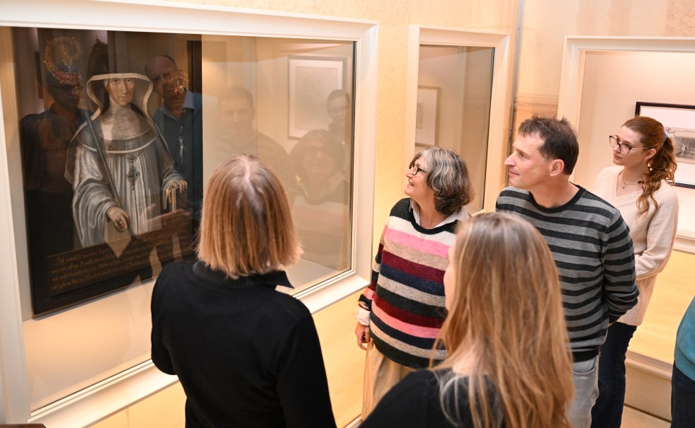 Eine Gruppe von Menschen betrachtet ein Gemälde in einem Museum. Sie stehen vor einer Vitrine und diskutieren interessiert., © HdGBW/ Franziska Kraufmann Eine Gruppe von Menschen betrachtet ein Gemälde in einem Museum. Sie stehen vor einer Vitrine und diskutieren interessiert., © HdGBW/ Franziska Kraufmann
