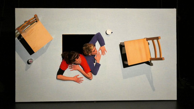 Two people are looking through a hole in a slanted wall. Two chairs and a cup are also attached to the wall., &copy; FITZ Das Theater animierter Formen