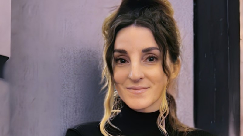 Porträt einer Frau mit hochgestecktem Haar und dunklem Oberteil vor neutralem Hintergrund., © Andrea A. Walter