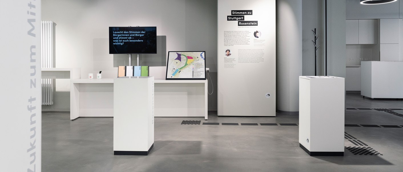 Moderne Ausstellung mit wei&szlig;en Podesten, Infotafeln und einem Bildschirm. Thema: Stimmen zu Stuttgart Rosenstein. Minimalistisches Design., &copy; Stadt Stuttgart / Dominique Brewing