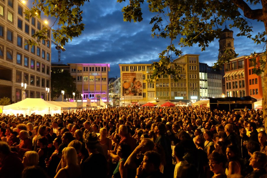 Große Menschenmenge bei einem nächtlichen Festival in der Stadt. Beleuchtete Gebäude und Zelte schaffen eine lebendige Atmosphäre., © Forum der Kulturen Stuttgart e. V. Große Menschenmenge bei einem nächtlichen Festival in der Stadt. Beleuchtete Gebäude und Zelte schaffen eine lebendige Atmosphäre., © Forum der Kulturen Stuttgart e. V.