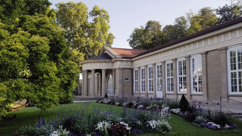 Der Kursaal Bad Cannstatt mit klassischer Architektur, großen Fenstern und einem gepflegten Garten im Vordergrund, umgeben von Bäumen., © Stuttgart-Marketing GmbH