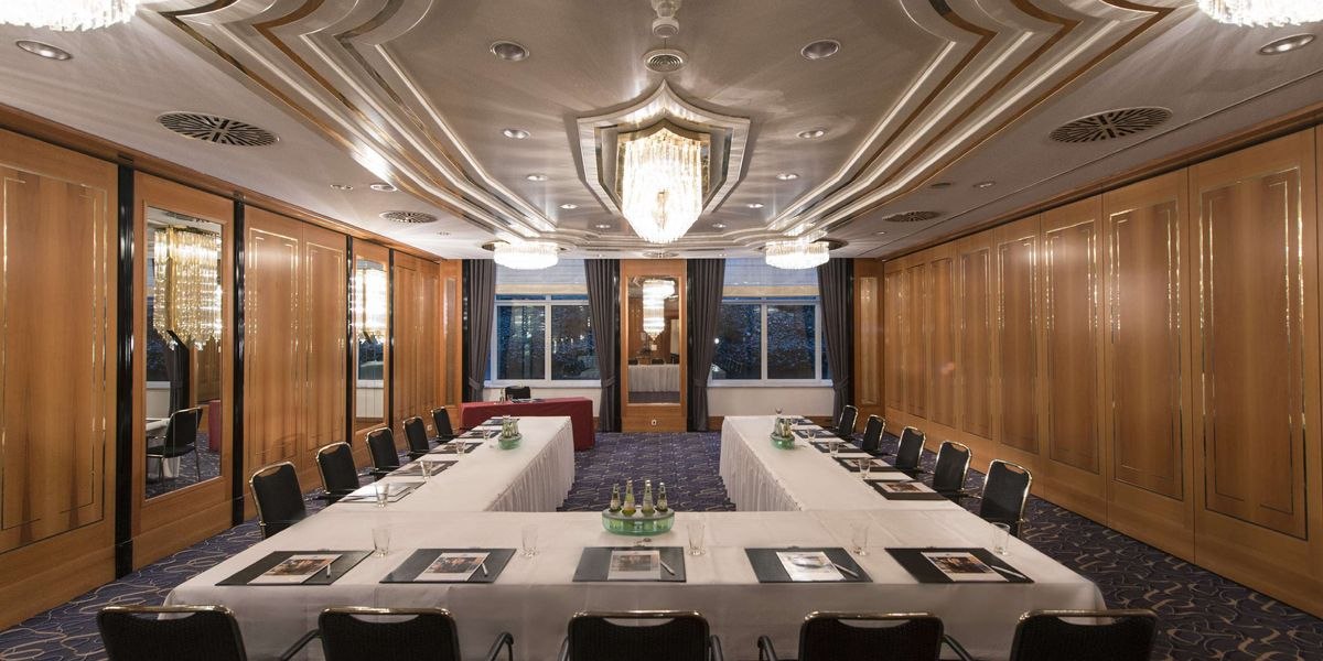 Elegant meeting room with U-shaped table arrangement, chandeliers and wooden walls. The room is prepared for a conference., © Maritim Hotelgesellschaft mbH Elegant meeting room with U-shaped table arrangement, chandeliers and wooden walls. The room is prepared for a conference., © Maritim Hotelgesellschaft mbH