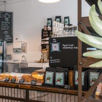 Ein gem&uuml;tliches Caf&eacute; mit Theke, Geb&auml;ckauslage und Getr&auml;nkekarte. Pflanzen schm&uuml;cken den Raum, und eine Tafel zeigt das Men&uuml; an., &copy; SMG, Sarah Schmid