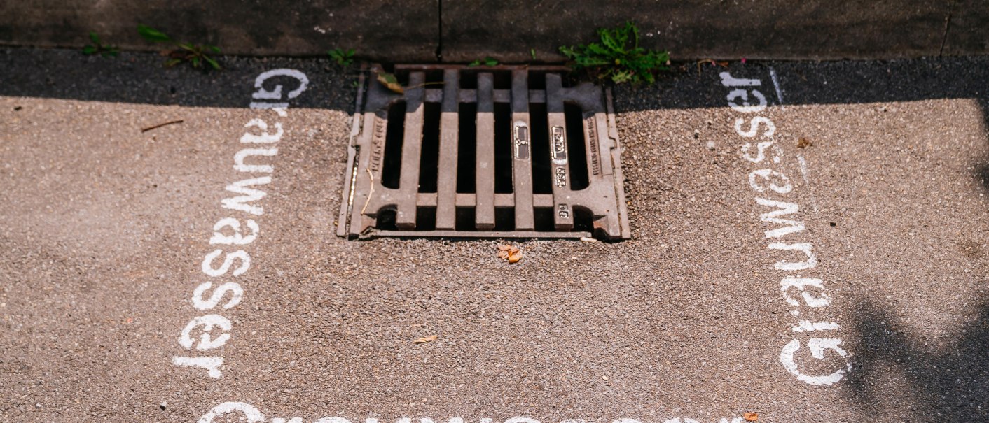Abflussgitter auf einem Parkplatz, umgeben von der Aufschrift 'Grauwasser' auf dem Asphalt., © Stuttgart-Marketing GmbH, Thomas Niedermüller Abflussgitter auf einem Parkplatz, umgeben von der Aufschrift 'Grauwasser' auf dem Asphalt., © Stuttgart-Marketing GmbH, Thomas Niedermüller