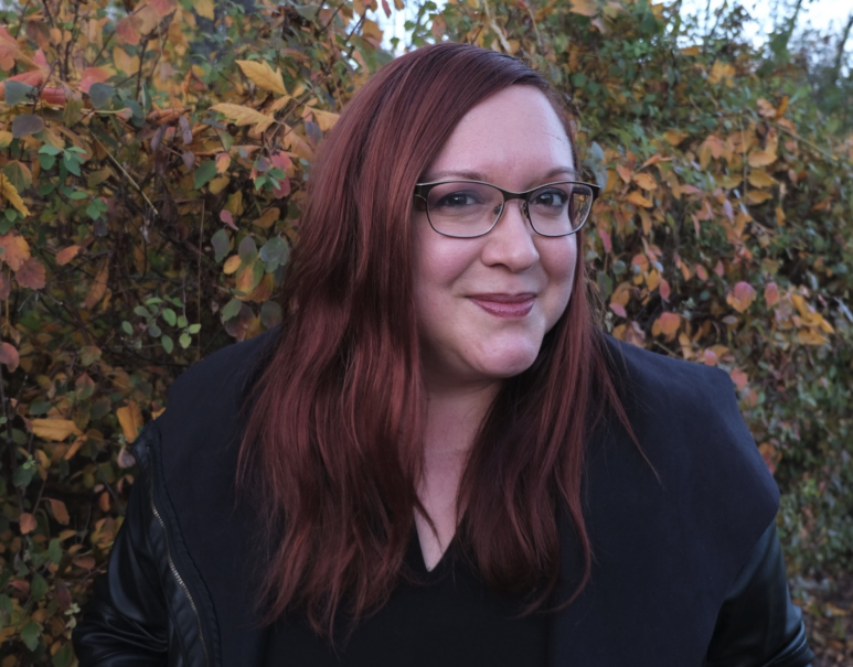 Eine Frau mit roten Haaren und Brille l&auml;chelt vor einem herbstlichen Hintergrund mit bunten Bl&auml;ttern., &copy; Caroline Jakobsohn
