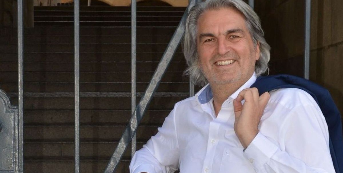 Ein Mann in weißem Hemd lehnt lächelnd an einem Gittertor. Im Hintergrund sind Treppen und ein historisches Gebäude zu sehen., © Wolfgang Seljé Ein Mann in weißem Hemd lehnt lächelnd an einem Gittertor. Im Hintergrund sind Treppen und ein historisches Gebäude zu sehen., © Wolfgang Seljé