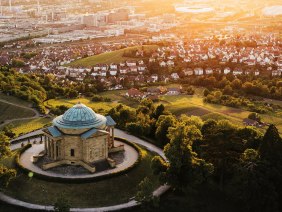 Luftaufnahme der Grabkapelle auf dem Württemberg in Stuttgart, umgeben von Weinbergen und Stadtlandschaft im Sonnenuntergang., © SMG, Cornelius Bierer Luftaufnahme der Grabkapelle auf dem Württemberg in Stuttgart, umgeben von Weinbergen und Stadtlandschaft im Sonnenuntergang., © SMG, Cornelius Bierer