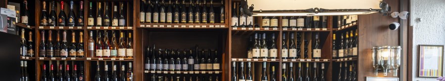 Counter at Weinhaus Stetter with shelves full of wine bottles and a wooden counter. A sign reading 'Weinhaus Stetter' hangs from the ceiling., © SMG Stuttgart Marketing GmbH - Sarah Schmid