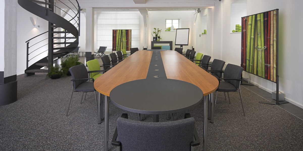 Modern conference room with oval table, gray and green chairs, spiral staircase and bamboo decor., © Schlosshotel Monrepos Modern conference room with oval table, gray and green chairs, spiral staircase and bamboo decor., © Schlosshotel Monrepos