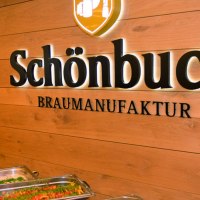 Interior view of a brewery with buffet. "Schönbuch Braumanufaktur" is written on the wooden wall. In the foreground are dishes in warming containers., © © Schönbuchbrauerei, Sebastian Berger Interior view of a brewery with buffet. "Schönbuch Braumanufaktur" is written on the wooden wall. In the foreground are dishes in warming containers., © © Schönbuchbrauerei, Sebastian Berger