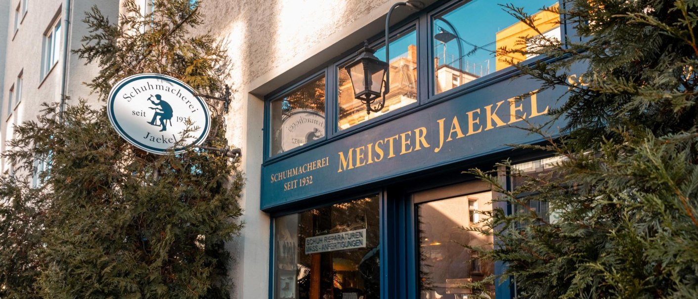 Entrance to the Meister Jaekel shoemaker's shop with a sign indicating the year it was founded, 1932. Surrounded by green plants., © SMG Stuttgart Marketing GmbH - Sarah Schmid Entrance to the Meister Jaekel shoemaker's shop with a sign indicating the year it was founded, 1932. Surrounded by green plants., © SMG Stuttgart Marketing GmbH - Sarah Schmid