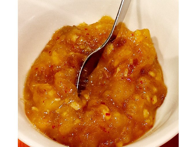 Ein L&ouml;ffel steckt in einer Schale mit Mango-Chutney. Die Mischung aus s&uuml;&szlig;en und w&uuml;rzigen Aromen ist typisch f&uuml;r die indische K&uuml;che., &copy; Kultweine-Kochwelten-Kunst&uuml;cke - Kochschule Sonja Lenz