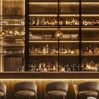 Elegante Bar mit indirekter Beleuchtung, Regale voller Flaschen und Gl&auml;ser, stilvolle Hocker und Pflanzen dekorieren den Raum., &copy; KI-generiert