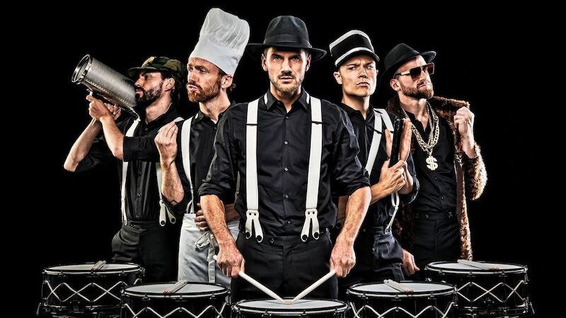 Five men in black clothing and various hats pose with drums. They wear accessories such as a chef's hat and a gold chain., &copy; Theaterhaus Stuttgart e.V.