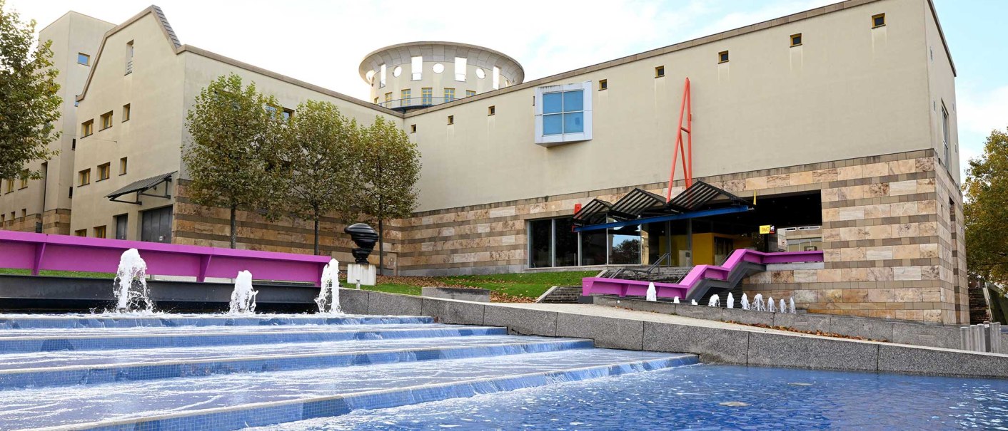 The Haus der Geschichte features modern architecture with a fountain in the foreground. Trees line the building, which impresses with its clear lines and colors., © hdgbw