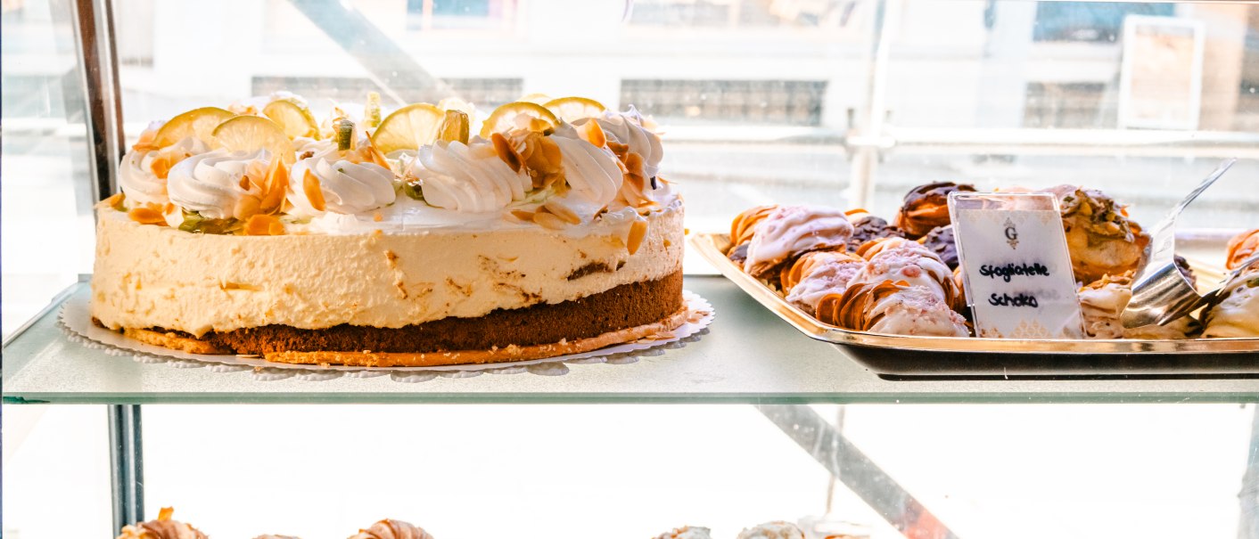 Eine Vitrine zeigt eine Zitronentorte und verschiedene Gebäcksorten wie Sfogliatelle mit Zitronen- und weißer Schokolade in einem Café., © SMG, Sarah Schmid