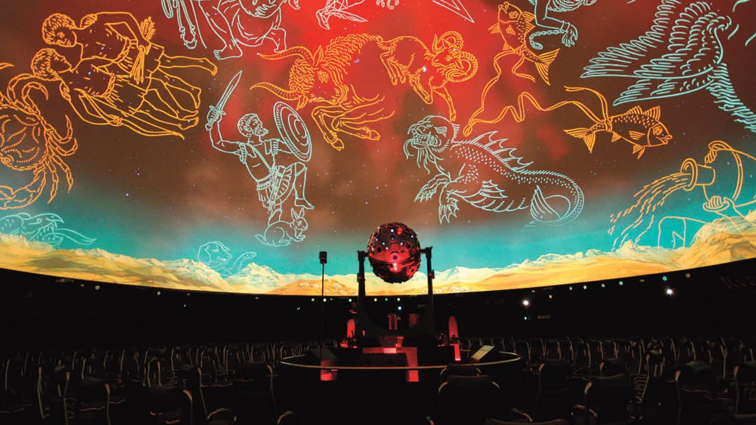 Innenansicht eines Planetariums mit leeren Sitzen und projizierten Sternbildern an der Kuppel. Ein Projektor steht in der Mitte., © Planetarium Stuttgart