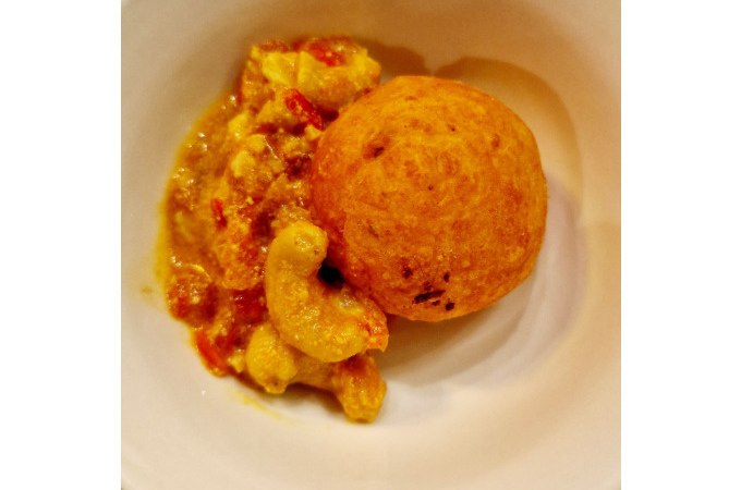 Ein Teller mit einem frittierten Ball und einer cremigen, gelben So&szlig;e mit Gem&uuml;se. Das Gericht ist Teil eines indischen Kochkurses., &copy; Kultweine-Kochwelten-Kunst&uuml;cke - Kochschule Sonja Lenz