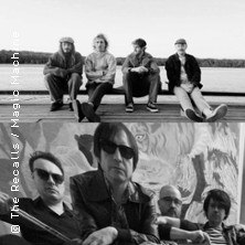 Zwei Schwarz-Weiß-Fotos: Oben sitzen vier Personen auf einem Steg am Wasser. Unten posieren vier Personen vor einer bemalten Wand., © links im Bild