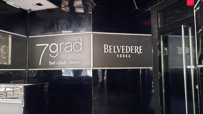 Eingang zur 7grad Bar mit schwarzem Interieur und Belvedere Vodka Werbung. Glastür mit "Ziehen"-Schild sichtbar., © SMG Eingang zur 7grad Bar mit schwarzem Interieur und Belvedere Vodka Werbung. Glastür mit "Ziehen"-Schild sichtbar., © SMG