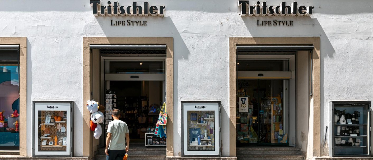 Gesch&auml;ftseingang von 'Tritschler Life Style' mit Schaufenstern und einem Mann, der hineingeht. Pl&uuml;schtiere h&auml;ngen am Eingang., &copy; Stuttgart-Marketing GmbH, Sarah Schmid