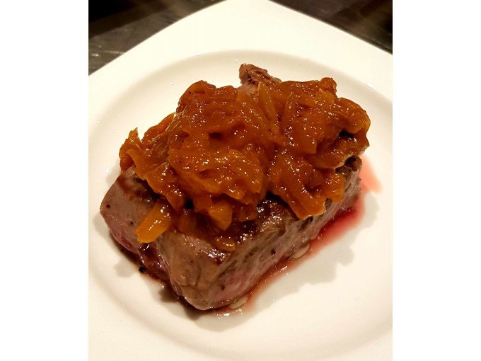 A juicy piece of meat, garnished with an onion sauce, served on a white plate., © Kultweine-Kochwelten-Kunstücke - Kochschule Sonja Lenz A juicy piece of meat, garnished with an onion sauce, served on a white plate., © Kultweine-Kochwelten-Kunstücke - Kochschule Sonja Lenz
