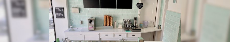 Ice cream parlor with counter, ice cream machine, coffee maker and ice cream cones. Pastel-colored tiles and lamps. Black boards with ice cream offers., © Zur Schleckerei Ice cream parlor with counter, ice cream machine, coffee maker and ice cream cones. Pastel-colored tiles and lamps. Black boards with ice cream offers., © Zur Schleckerei