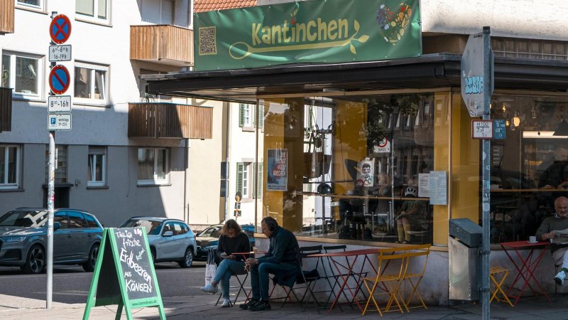 Ein Café namens Kantinchen mit gelbem und grünem Schild. Draußen sitzen Menschen an bunten Tischen. Verkehrsschilder und Autos sind zu sehen., © SMG, Sarah Schmid