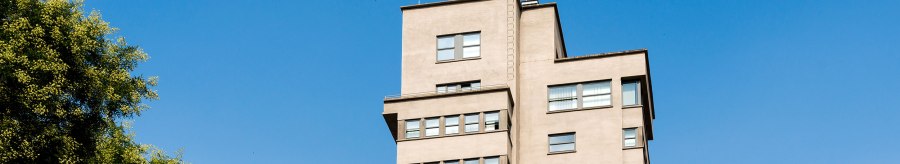 Der Tagblatt-Turm in Stuttgart erhebt sich vor einem klaren blauen Himmel, umgeben von grünen Bäumen., © TMBW, Gregor Lengler