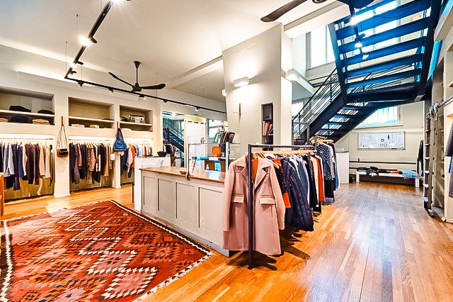 Modern clothing store with wooden floor, carpet, clothes racks and a staircase in the background., © Mario P. Rodrigues Modern clothing store with wooden floor, carpet, clothes racks and a staircase in the background., © Mario P. Rodrigues