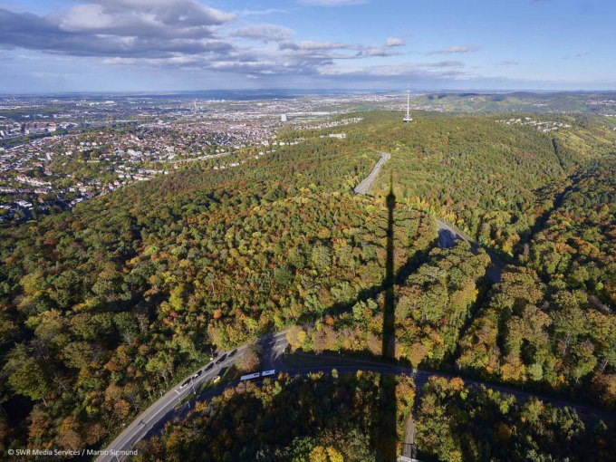 Luftaufnahme des Stuttgarter Fernsehturms, dessen Schatten über einen bewaldeten Hügel fällt. Im Hintergrund sind Stadt und Hügel zu sehen., © SWR Media Services GmbH / Fernsehturm Stuttgart Luftaufnahme des Stuttgarter Fernsehturms, dessen Schatten über einen bewaldeten Hügel fällt. Im Hintergrund sind Stadt und Hügel zu sehen., © SWR Media Services GmbH / Fernsehturm Stuttgart