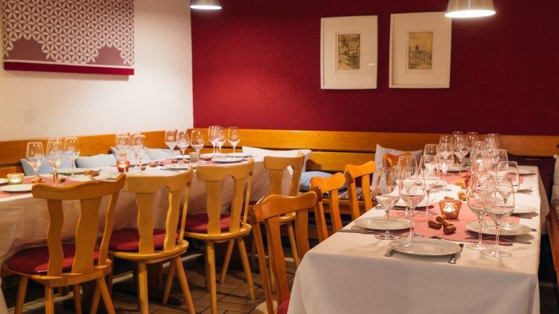 Comfortably laid table in a restaurant with wine glasses, candles and wooden furniture. The walls are decorated in red and white., &copy; 70469R! Weinbau Fabian Rajtschan